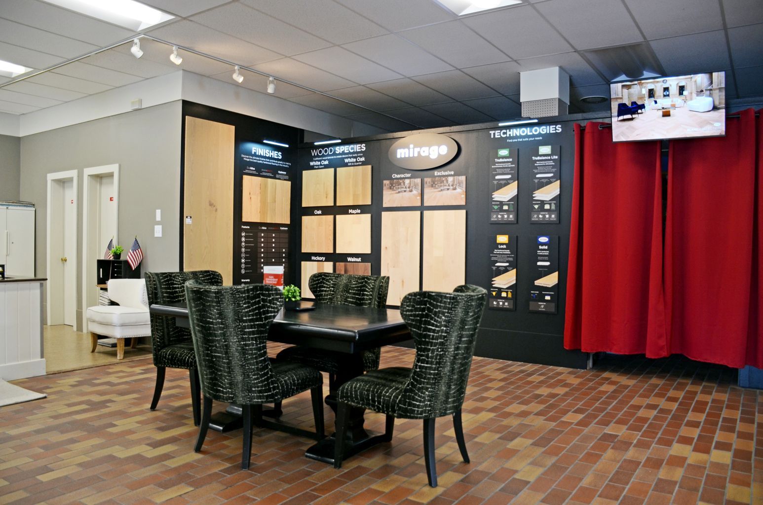 Indoor lounge with round table and chairs, menu boards, and a red curtain backdrop