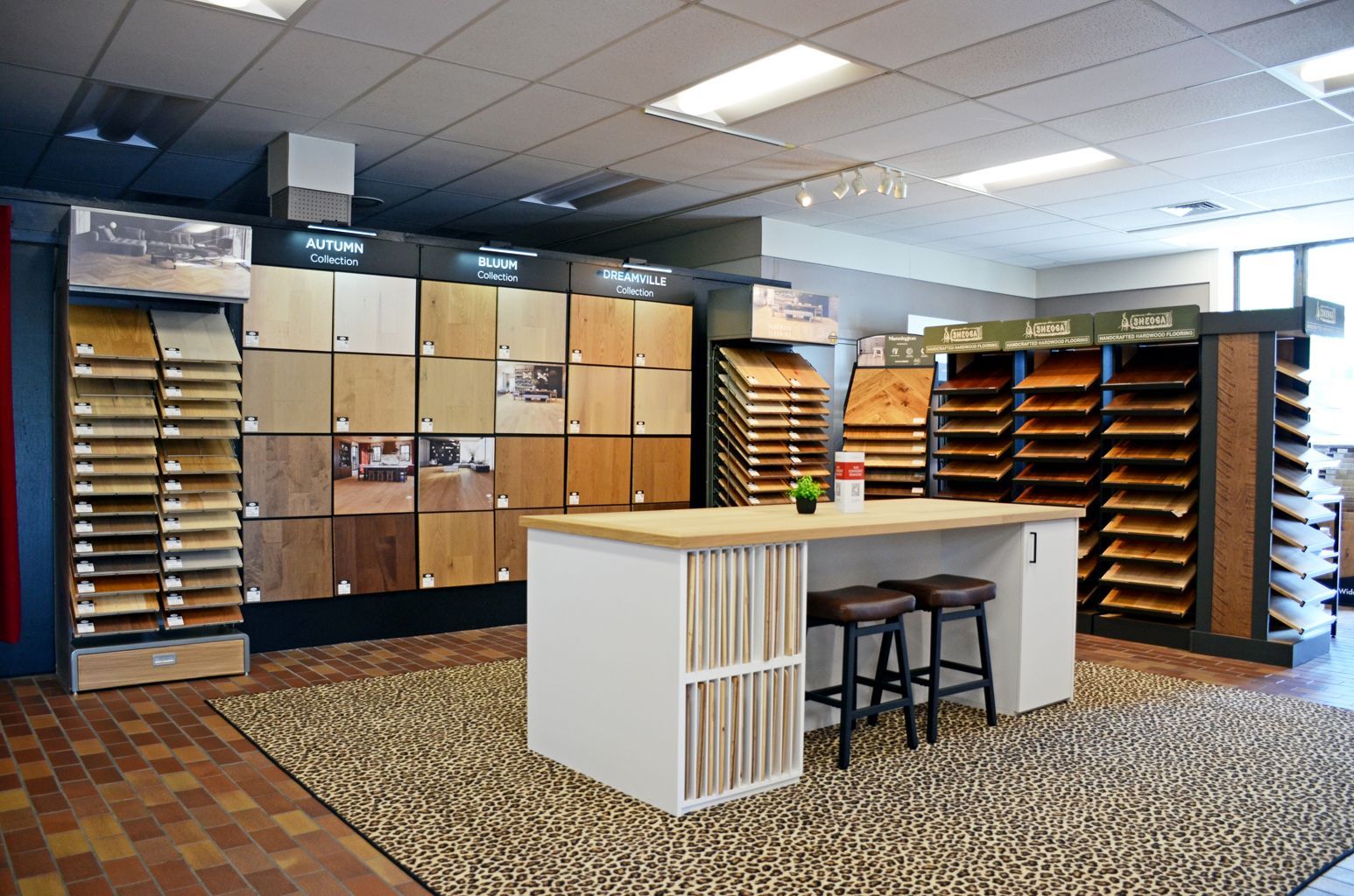 Furniture showroom with display shelves, sample cabinets, and a central counter under bright lights