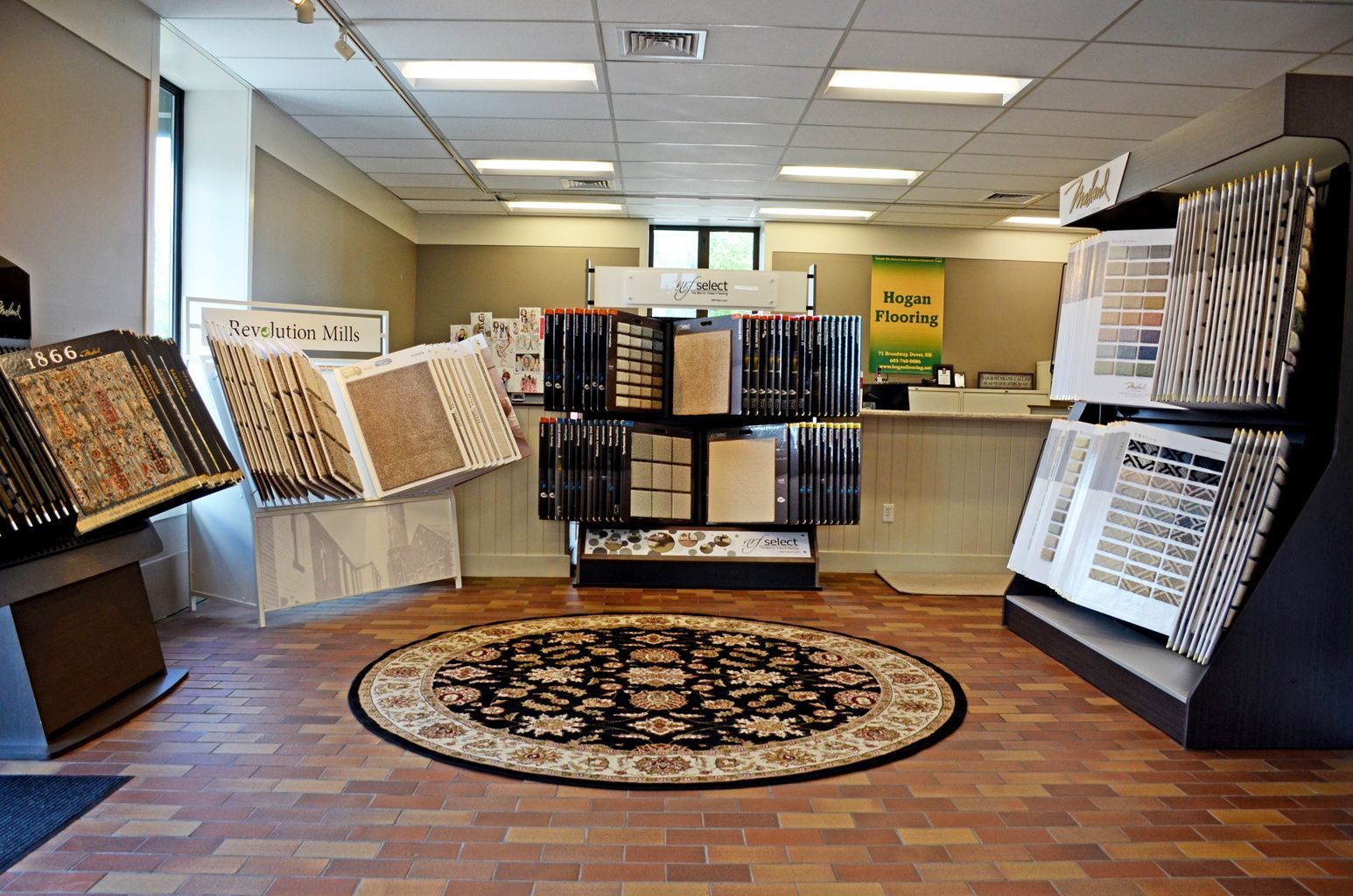 Carpet and flooring showroom with display racks and samples around a central rug.