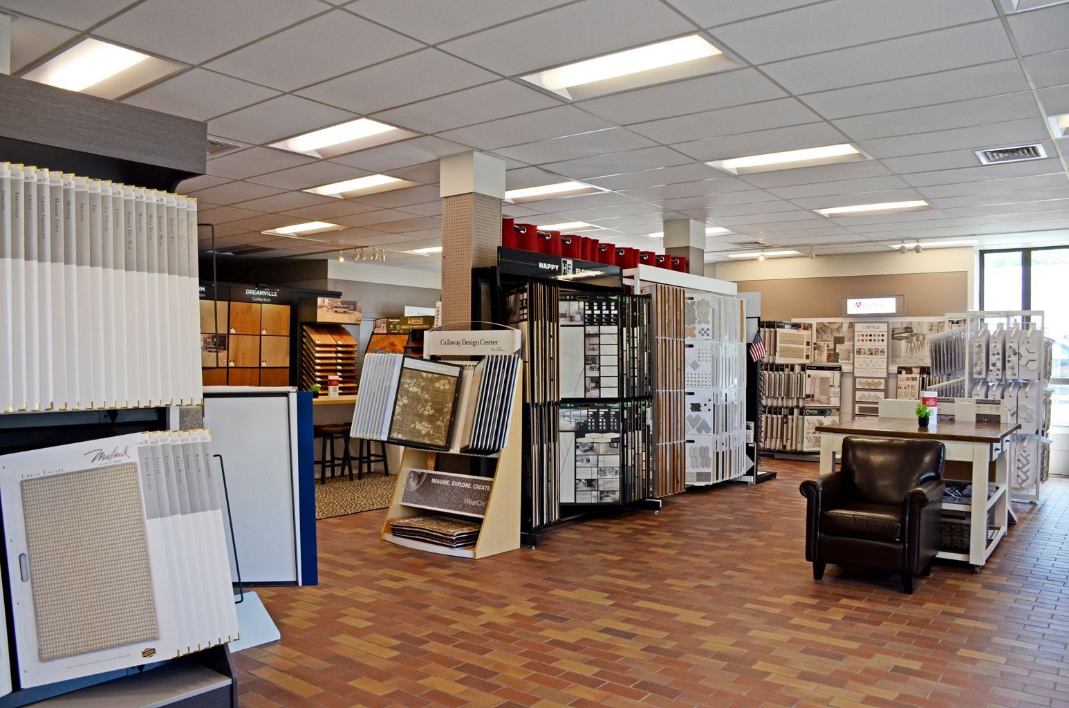 Carpet showroom with display panels, flooring samples, and chairs under bright ceiling lights