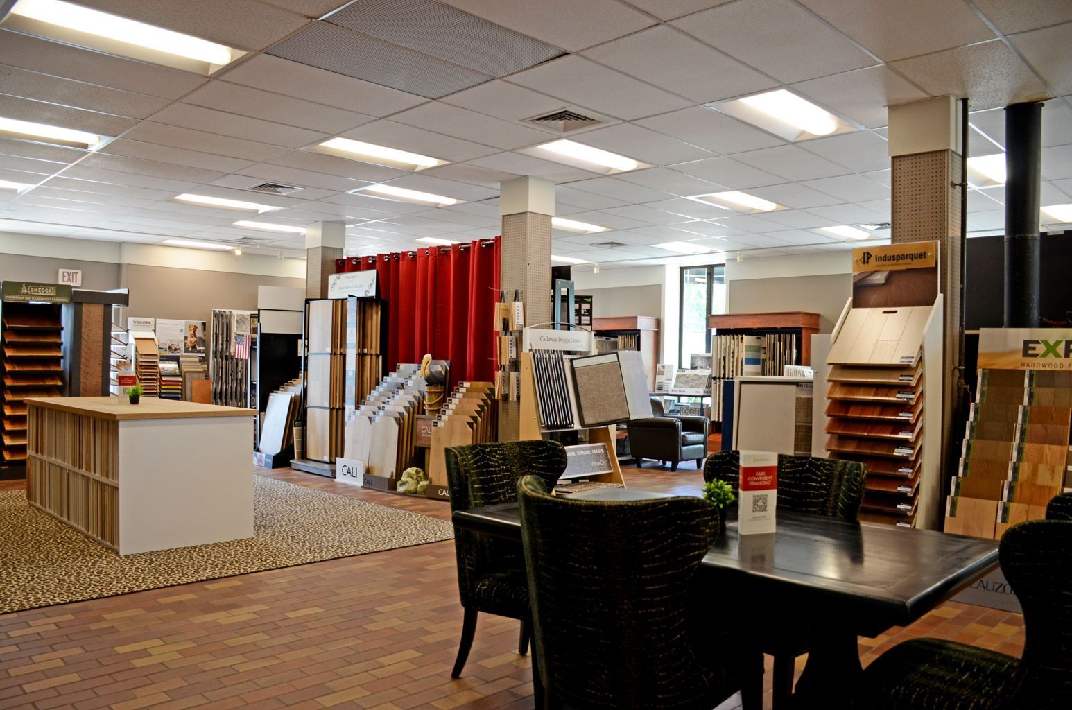 Interior of a carpet store with shelves, display tables, and samples under bright ceiling lights.