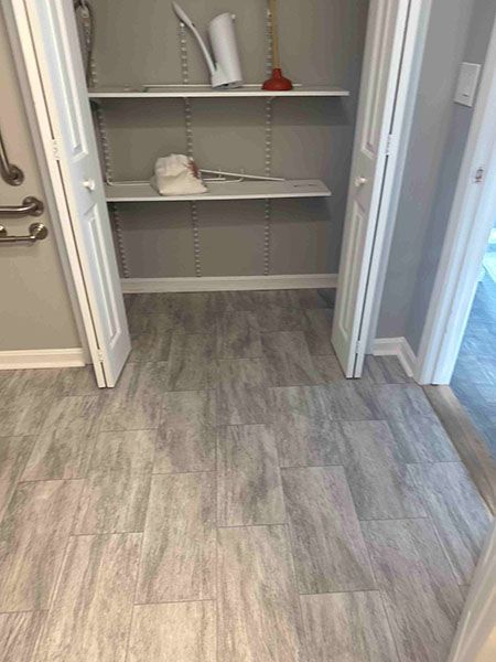 Closet with gray flooring, adjustable shelving, and white doors.