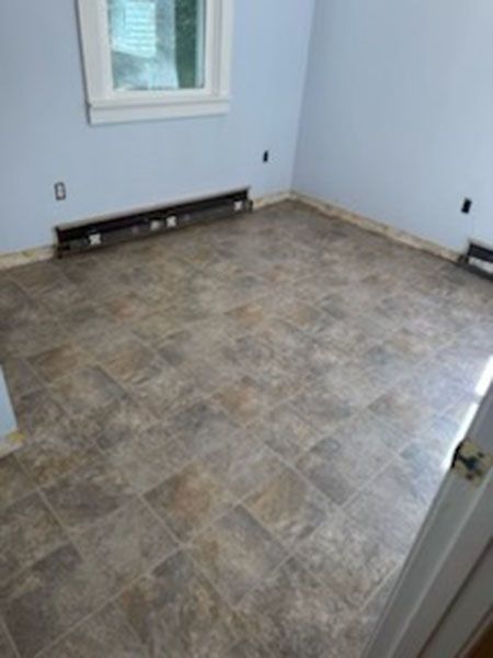 Empty room with blue walls, brown tile floor, window, and baseboard heaters.