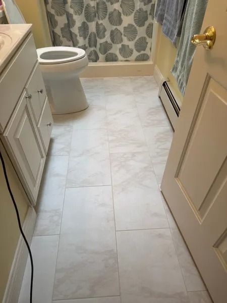Bathroom with white tile floor, toilet, and cabinet. Door is slightly ajar.
