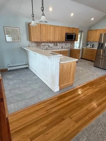 Kitchen with light wood cabinets, white island with countertop, tile floor, and hardwood floor transition.