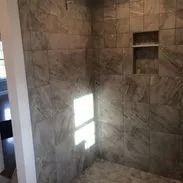 Tiled shower with a built-in shelf, light shining through the window.