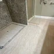 Shower with light-colored floor and gray tile accents, glass door, and gray shower wall.