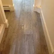 Hallway with light-colored, wood-look floor tiles and white walls.