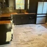 Kitchen with black cabinets, stainless steel appliances, wood countertops, and light tile flooring.