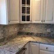Kitchen countertop with white cabinets and a mosaic backsplash.