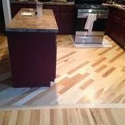 Kitchen with a maroon island, black stove, and a light wood floor with a unique pattern.