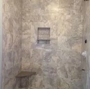Gray tiled shower with a built-in bench and shelf.