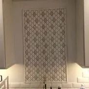 Kitchen backsplash with diamond-patterned tiles, framed within a white border, above the sink.