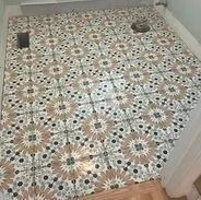 Patterned ceramic floor tiles in a room with a toilet, varying shades of brown, gray, and white.