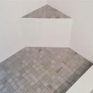 Room with tiled floor and gray triangle on white wall.