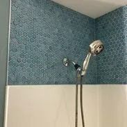 Shower with teal hexagon tile wall, white tub, and chrome showerhead.