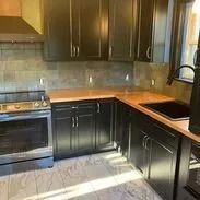 Kitchen with dark cabinets, stainless steel appliances, and wood countertop.