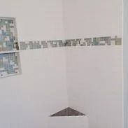 A white wall with art made of paper squares. A small gray triangle sits on the bottom.