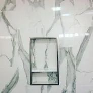 White marble tile shower with a recessed shelf.