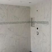 White tiled shower with a decorative horizontal tile strip and built-in niche.