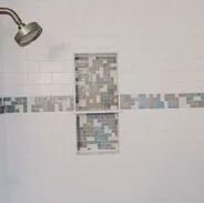Shower with white subway tile, mosaic accent strip, and built-in shelf with mosaic tile. Chrome shower head.