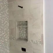 Shower interior with tiled walls, built-in niche, and a showerhead.