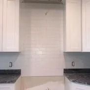 White kitchen cabinets and backsplash with dark countertops.