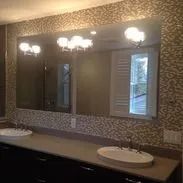 Bathroom with large mirror, two sinks, decorative tile, and sconce lighting.