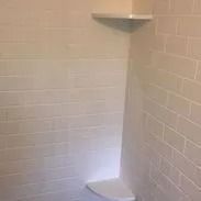 White-tiled shower with corner shelves.