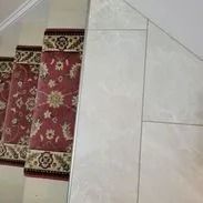 Red carpeted stairs with white tile next to them.