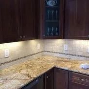 Kitchen with granite countertops, dark wood cabinets, and tiled backsplash.