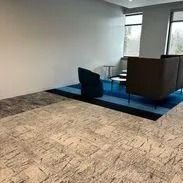Beige and blue carpeted office waiting area with chairs and a large window.