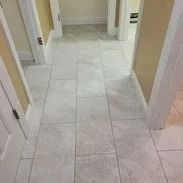 Hallway with light gray tile flooring, beige walls, and white door frames.