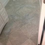 Gray tiled floor in a room, with white door and trim visible.