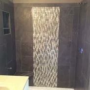 Shower with dark gray walls, a decorative vertical tile strip, and a built-in shelf.