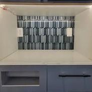 Gray and white kitchen backsplash with cabinets below.