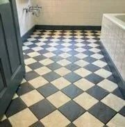 Black and white checkered tile floor in a bathroom, with a dark border and partial view of a white tub.