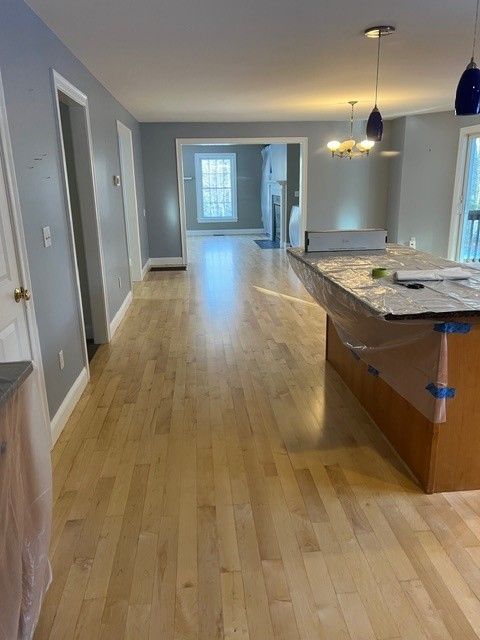 Hardwood floors in a house. Gray walls, kitchen island. View through doorways to a fireplace.