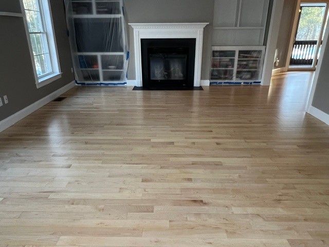 Wooden floor in a room with a fireplace and built-in shelves.