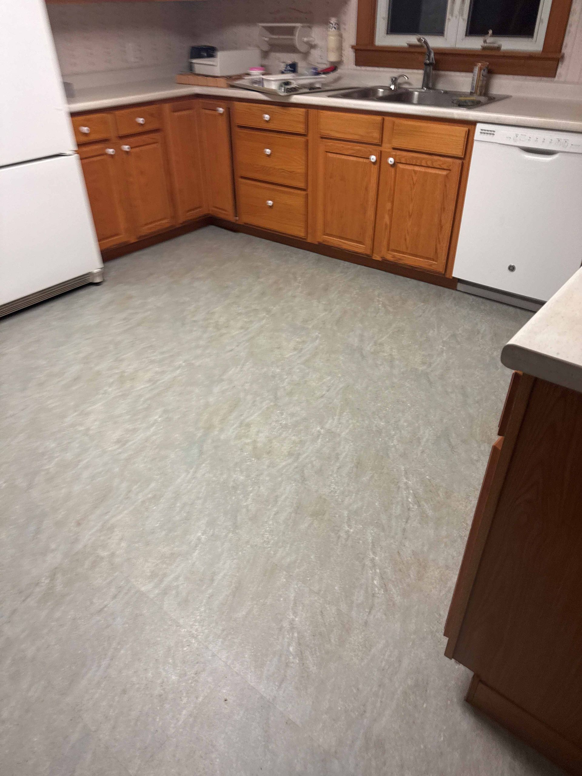 Kitchen with wooden cabinets, gray flooring, and a white refrigerator.