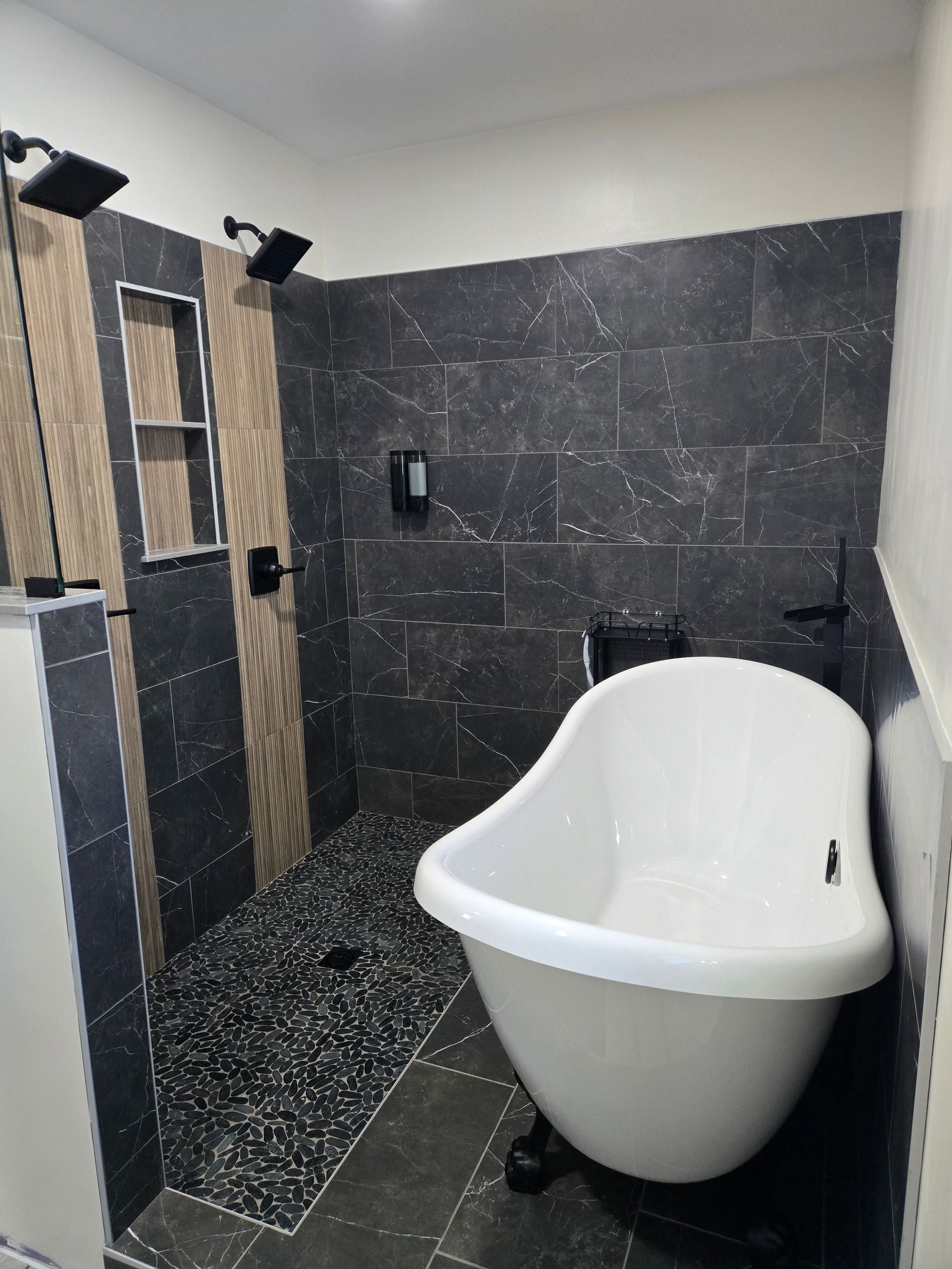Bathroom with dark gray tile shower, clawfoot tub, and two showerheads.