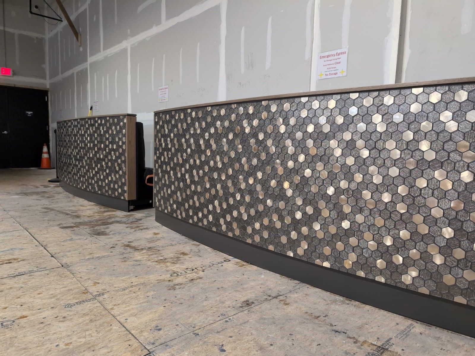 Two reception desks with mosaic tile fronts in a construction area.