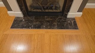 Fireplace with marble tile hearth on bamboo flooring.