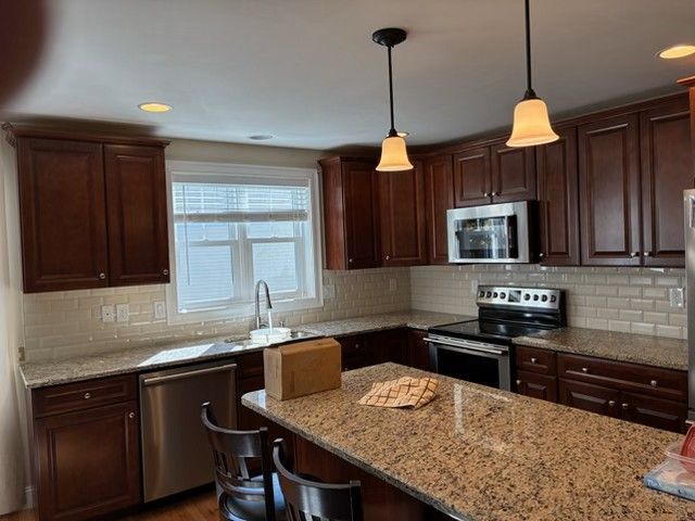 Kitchen with dark brown cabinets, granite countertops, and stainless steel appliances.