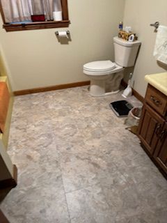 Bathroom with a toilet, sink, and patterned flooring.