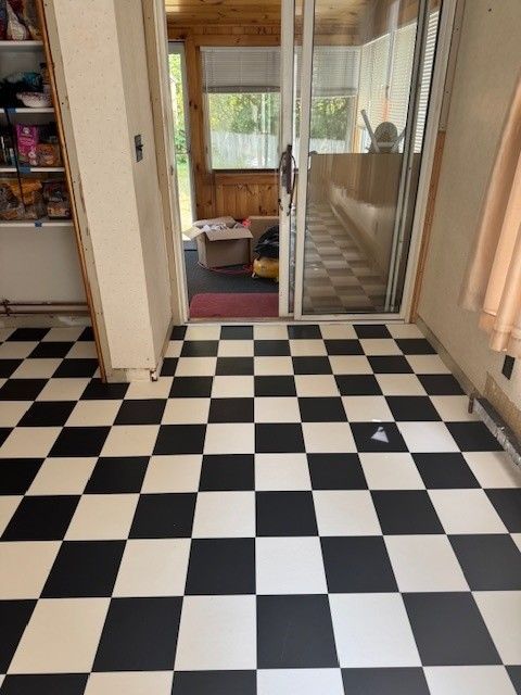 Black and white checkered floor in room with open doorway to a sunroom.