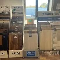 Displays of flooring samples in a store, showcasing various wood and tile textures and colors.