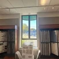 Interior view of a building with a large window and shelves displaying merchandise.