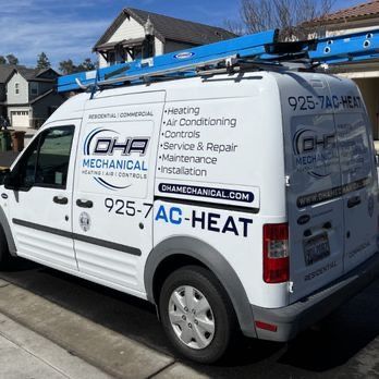 A white van with a ladder on top of it is parked in front of a house.
