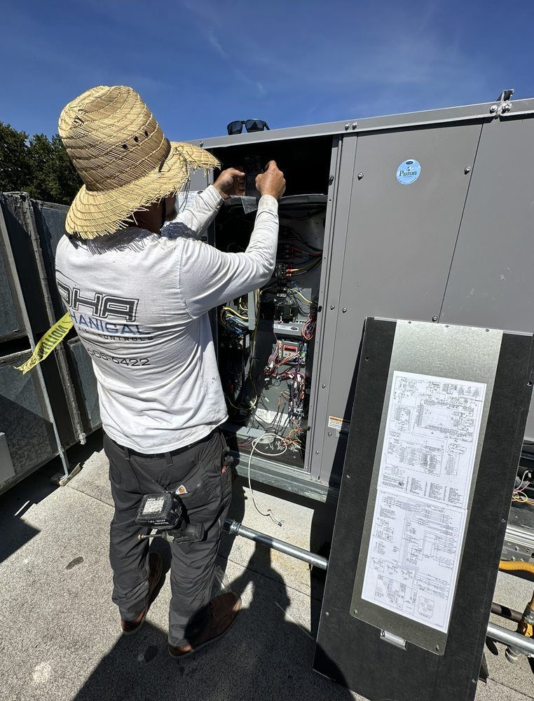 A man wearing a straw hat is working on an air conditioner.